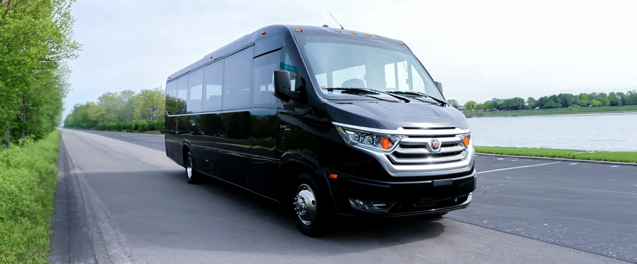 black commercial bus parked next to a lake and road